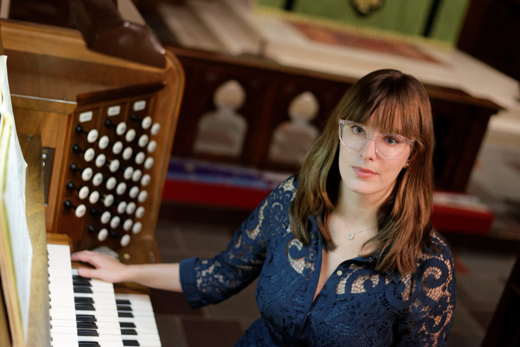 Sarah Johnson poses at a pipe organ.